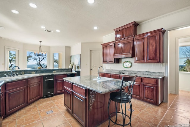 kitchen with pendant lighting, sink, backsplash, a center island with sink, and black electric cooktop