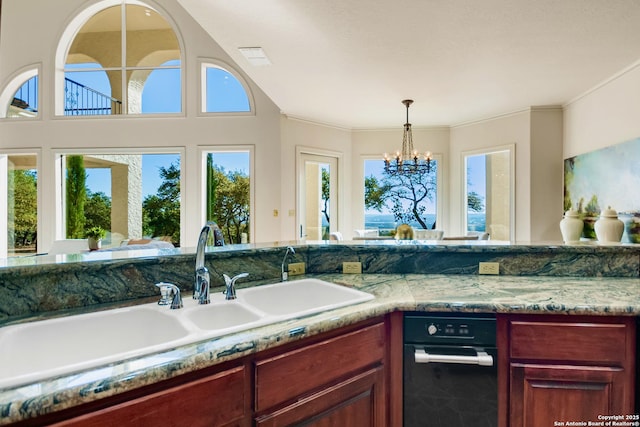 kitchen featuring pendant lighting, sink, a chandelier, ornamental molding, and light stone counters