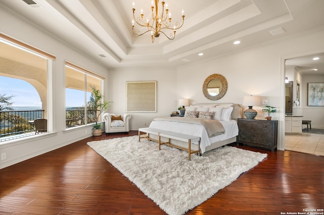 bedroom with a raised ceiling, dark hardwood / wood-style floors, and a notable chandelier