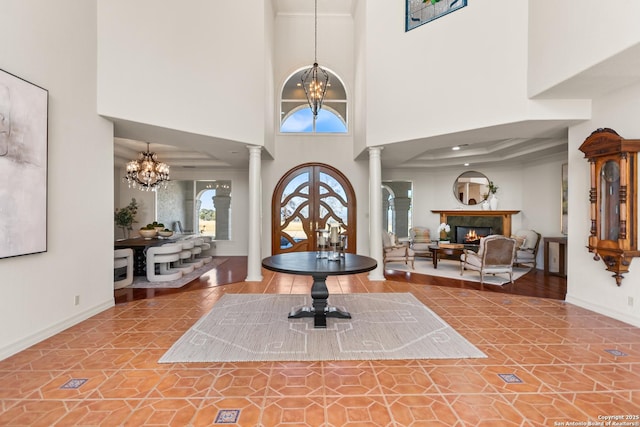 entrance foyer featuring decorative columns, a high ceiling, and a chandelier