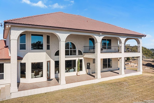 rear view of house featuring a balcony, a yard, and a patio area