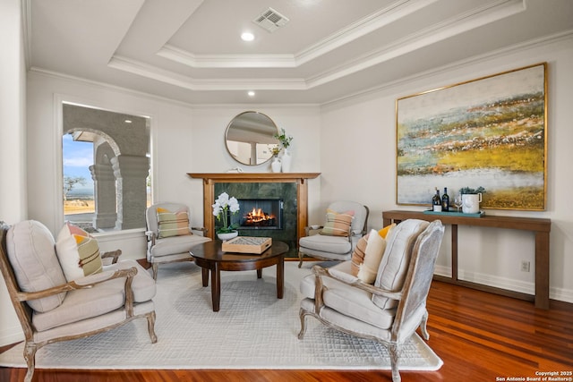 sitting room with a raised ceiling, ornamental molding, dark wood-type flooring, and a fireplace