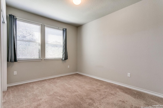 carpeted empty room featuring a textured ceiling