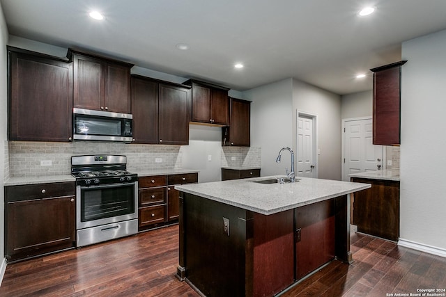 kitchen featuring appliances with stainless steel finishes, dark hardwood / wood-style floors, sink, and a center island with sink