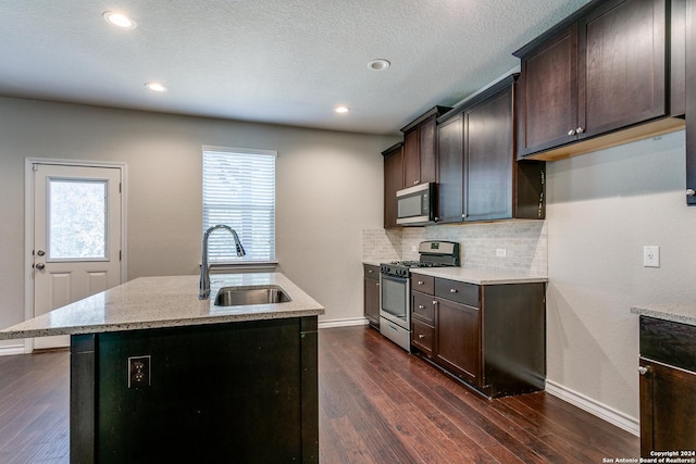 kitchen with tasteful backsplash, sink, a kitchen island with sink, stainless steel appliances, and dark brown cabinets