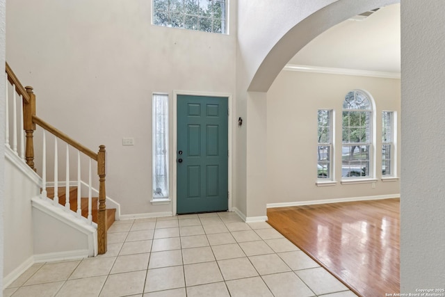 tiled entrance foyer featuring a towering ceiling, ornamental molding, and a healthy amount of sunlight