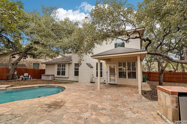 rear view of property featuring a fenced in pool and a patio area