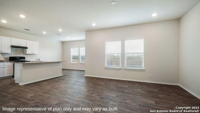 kitchen with white cabinets, dark hardwood / wood-style floors, a center island with sink, and range