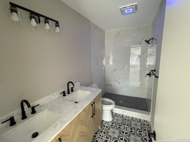 bathroom with tiled shower, vanity, toilet, and tile patterned floors