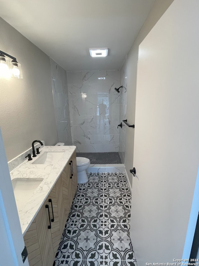 bathroom with vanity, a tile shower, tile patterned floors, and toilet