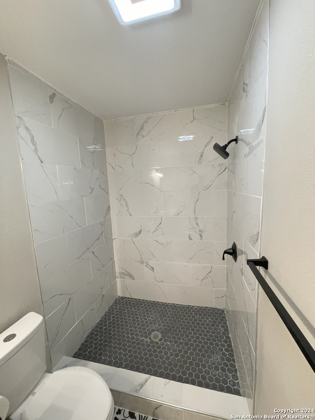 bathroom featuring tiled shower and toilet