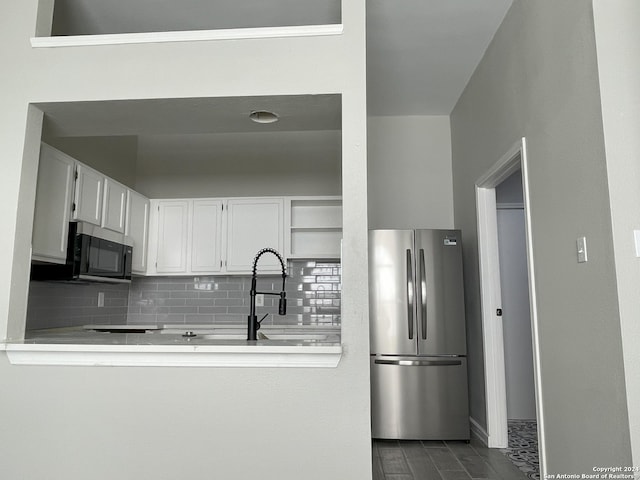 kitchen with appliances with stainless steel finishes, tasteful backsplash, white cabinetry, wood-type flooring, and sink