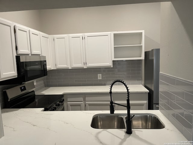 kitchen with white cabinetry, appliances with stainless steel finishes, sink, and light stone counters