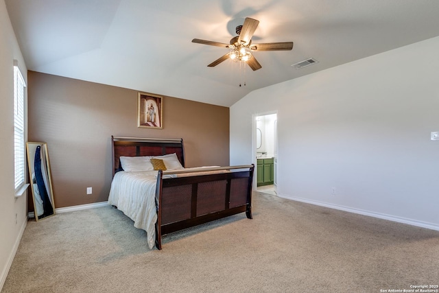 bedroom featuring ceiling fan, light colored carpet, lofted ceiling, and ensuite bath