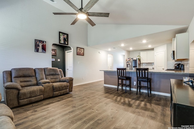 living room with high vaulted ceiling, hardwood / wood-style floors, and ceiling fan