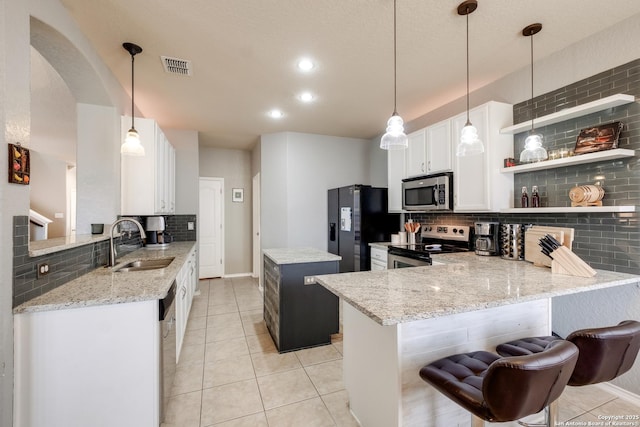 kitchen featuring stainless steel appliances, light stone countertops, white cabinets, decorative light fixtures, and kitchen peninsula