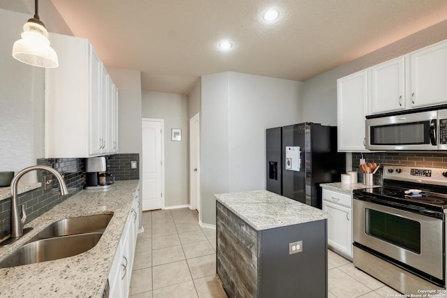 kitchen with sink, white cabinetry, light stone counters, a center island, and appliances with stainless steel finishes