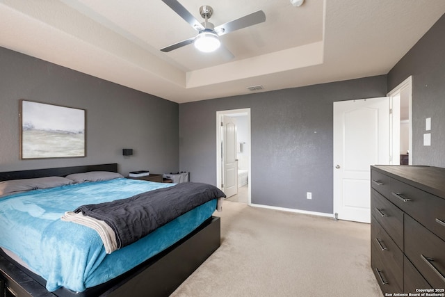 carpeted bedroom featuring ensuite bath, a raised ceiling, and ceiling fan