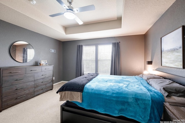 carpeted bedroom with ceiling fan, a raised ceiling, and a textured ceiling