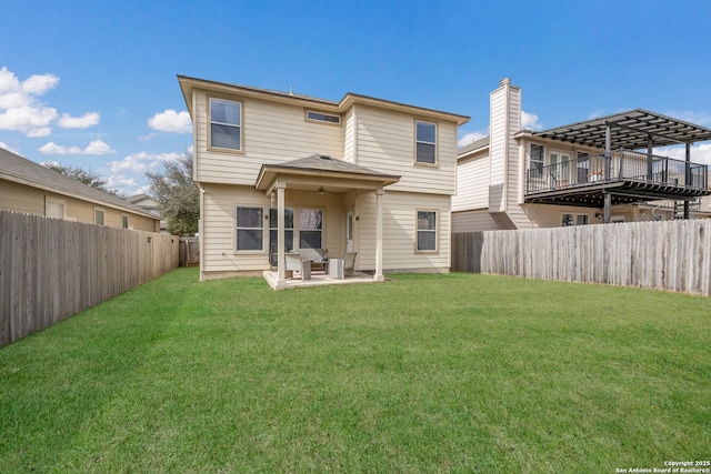 rear view of property featuring a lawn and a patio area