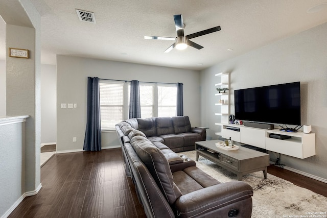 living room with a textured ceiling, dark hardwood / wood-style floors, and ceiling fan