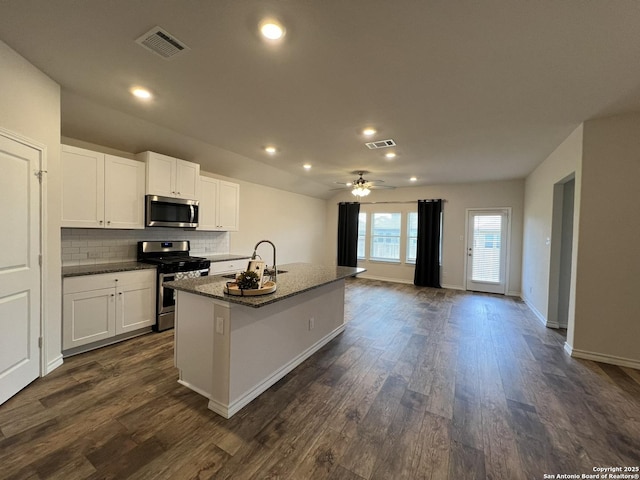 kitchen with dark wood-type flooring, sink, white cabinetry, a center island with sink, and appliances with stainless steel finishes