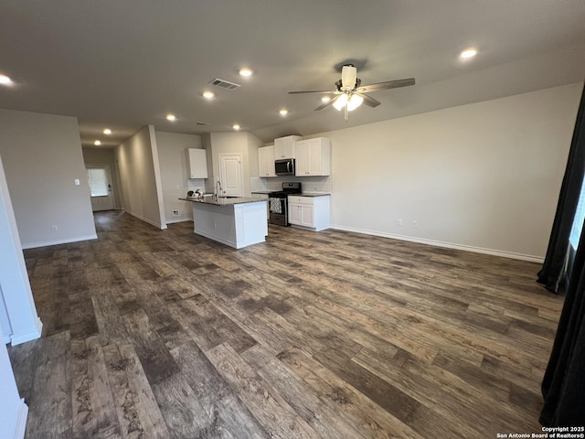 kitchen featuring appliances with stainless steel finishes, dark hardwood / wood-style floors, white cabinetry, sink, and a center island with sink