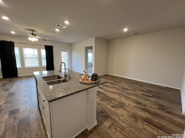 kitchen with sink, dark wood-type flooring, a kitchen island with sink, white cabinetry, and light stone countertops