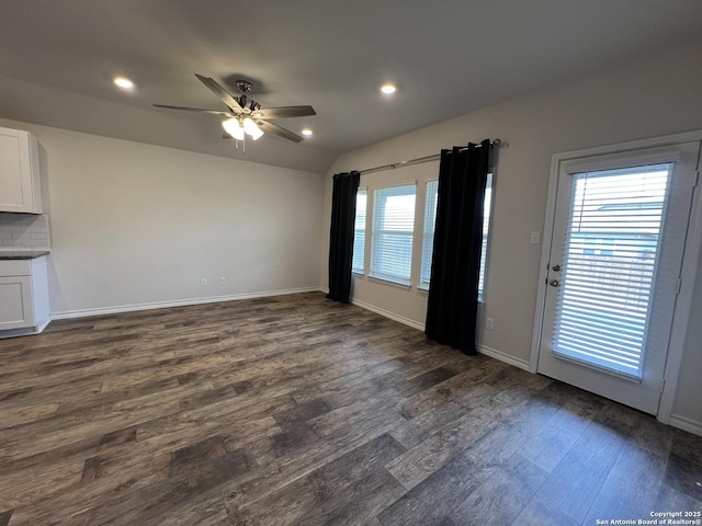 unfurnished living room featuring ceiling fan, dark hardwood / wood-style floors, and vaulted ceiling