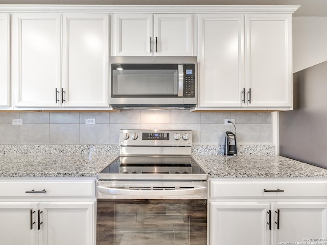 kitchen with white cabinetry, appliances with stainless steel finishes, light stone countertops, and backsplash