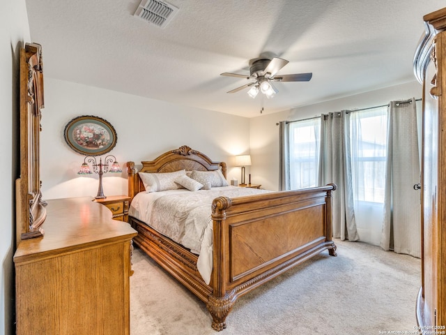 carpeted bedroom with ceiling fan and a textured ceiling