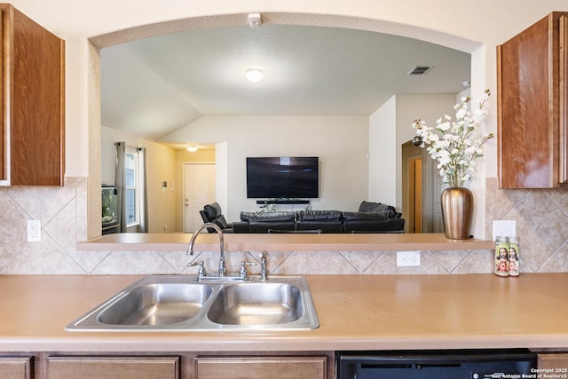 kitchen with dishwasher, lofted ceiling, sink, and backsplash