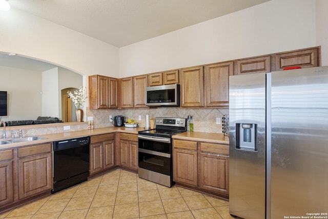 kitchen with stainless steel appliances, light tile patterned flooring, sink, and backsplash