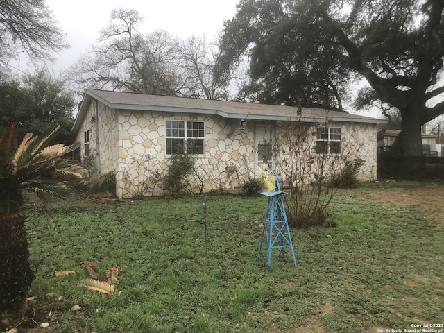 exterior space with stone siding and a yard