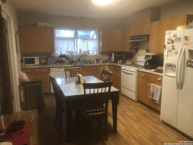 kitchen with light countertops, white appliances, a sink, and under cabinet range hood