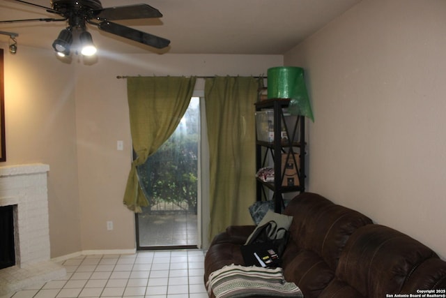 living room featuring ceiling fan, a fireplace, and light tile patterned floors