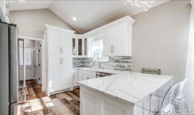 kitchen with sink, appliances with stainless steel finishes, light stone counters, white cabinets, and kitchen peninsula