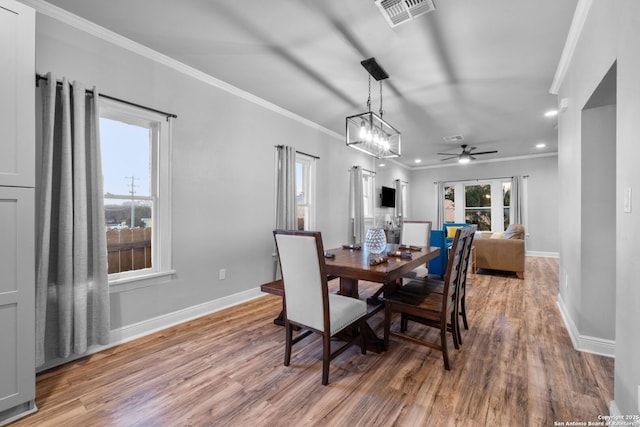 dining room with ceiling fan with notable chandelier, ornamental molding, and hardwood / wood-style floors