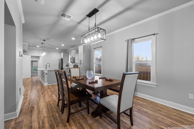 dining room with dark hardwood / wood-style flooring, sink, and crown molding