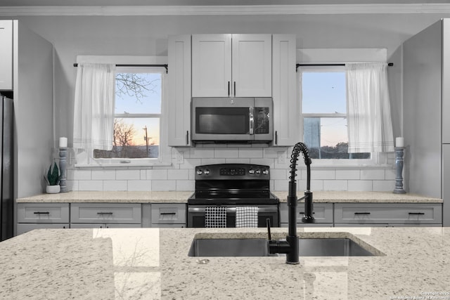 kitchen with ornamental molding, plenty of natural light, backsplash, and electric stove