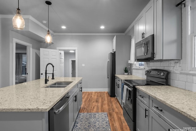 kitchen with sink, stainless steel appliances, light stone countertops, an island with sink, and decorative light fixtures