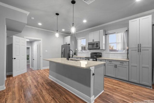 kitchen with appliances with stainless steel finishes, sink, gray cabinetry, light stone countertops, and a center island with sink