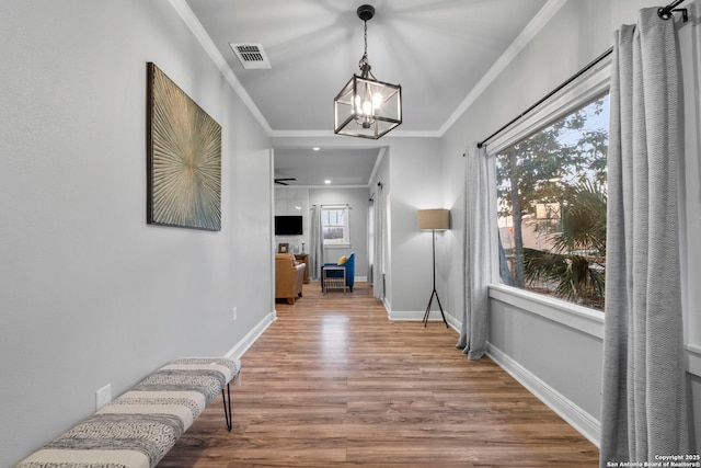 hallway featuring ornamental molding, hardwood / wood-style floors, and a notable chandelier