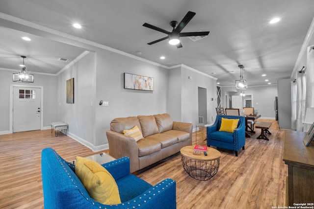 living room with ceiling fan with notable chandelier, ornamental molding, and light hardwood / wood-style floors