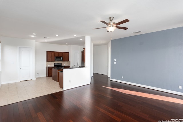 kitchen featuring sink, light hardwood / wood-style flooring, ceiling fan, stove, and tasteful backsplash