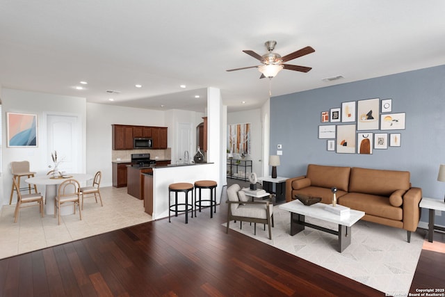 living room with ceiling fan and light hardwood / wood-style flooring