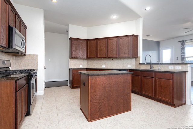 kitchen featuring sink, light tile patterned floors, appliances with stainless steel finishes, a center island, and kitchen peninsula