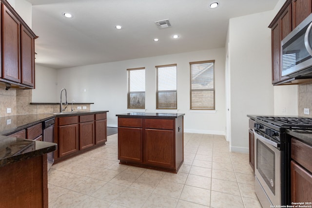 kitchen with light tile patterned flooring, sink, dark stone counters, stainless steel appliances, and decorative backsplash