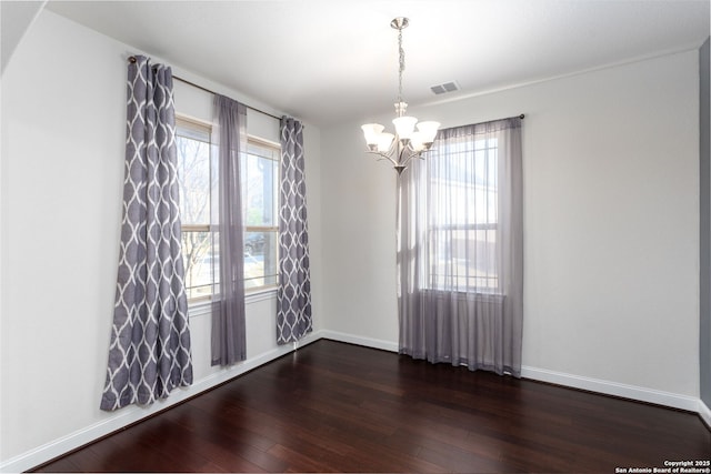 spare room with an inviting chandelier, dark hardwood / wood-style floors, and a healthy amount of sunlight