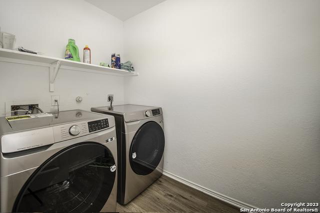 clothes washing area with dark hardwood / wood-style flooring and washer and dryer